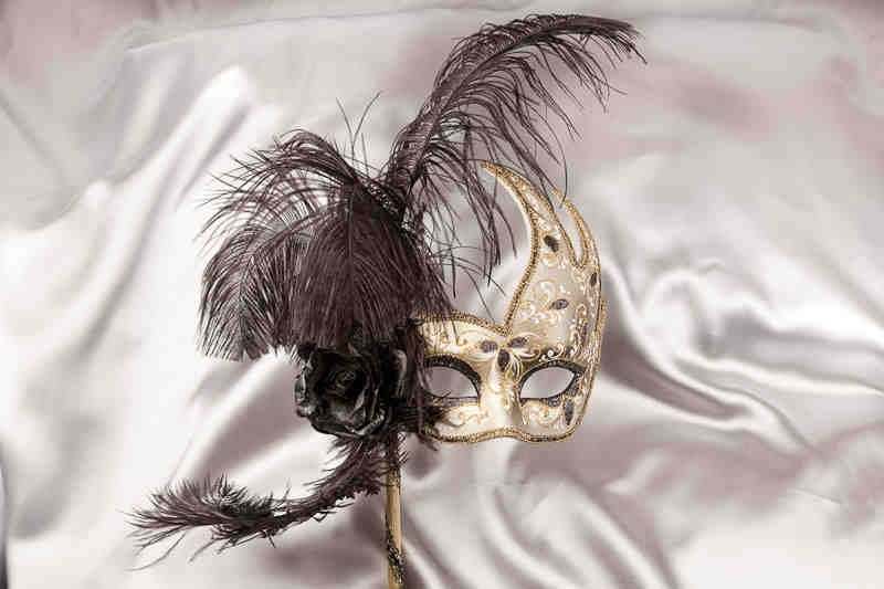 black and gold feathered mask on stick