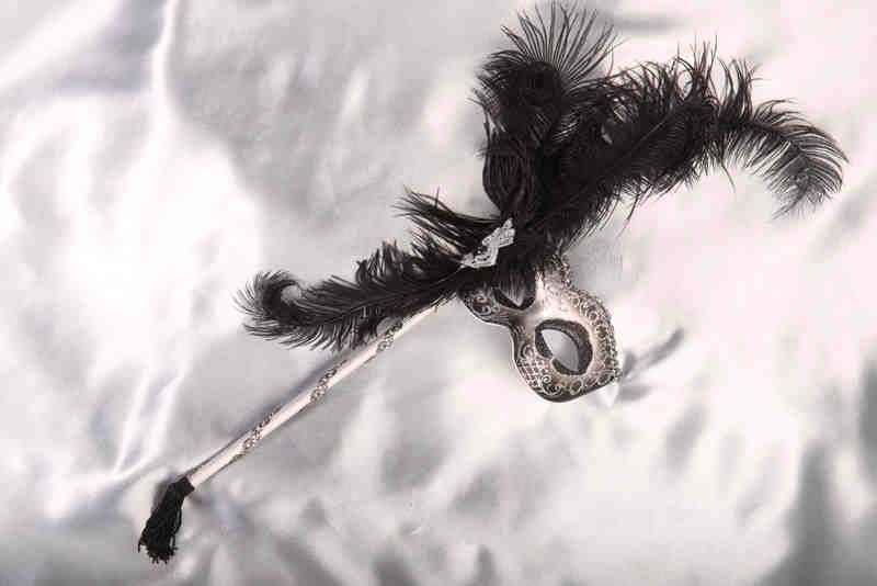 black and silver feathered mask on stick